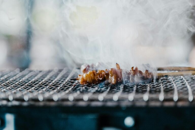 Delicious skewered meat grilling over open flames with smoky aroma.